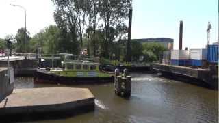 A Tugboat Towing A Big Barge With A Crane Through A Narrow Bridge