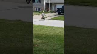 Boy rides bike down street and uses his front brakes to stop