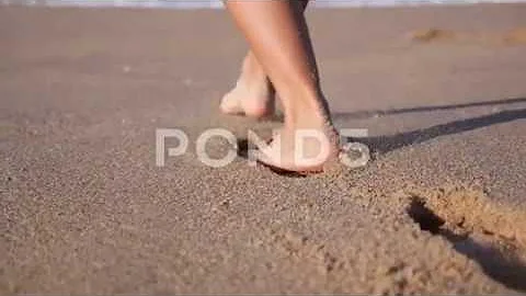 Woman Feet Walking On Beach Leaving Footprints In Sand