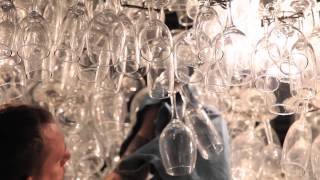 Workers hand wipe 12000 wine glasses hanging from the ceiling that had inadvertently gotten dusty during construction at the 
