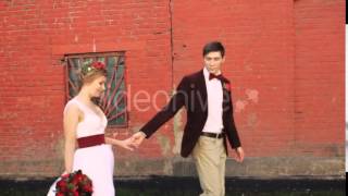 Bride and Groom Walking Along a Brick Red Wall