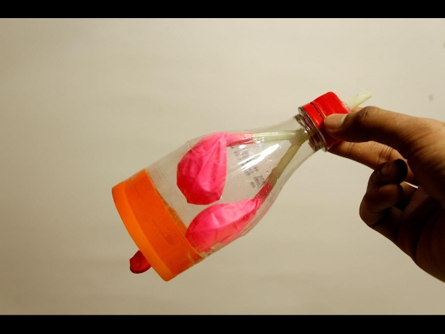 Boy blowing balloon from plastic car bottle at home stock photo