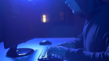 cybercrime hacking and technology crime male hacker in dark room writing code or using
