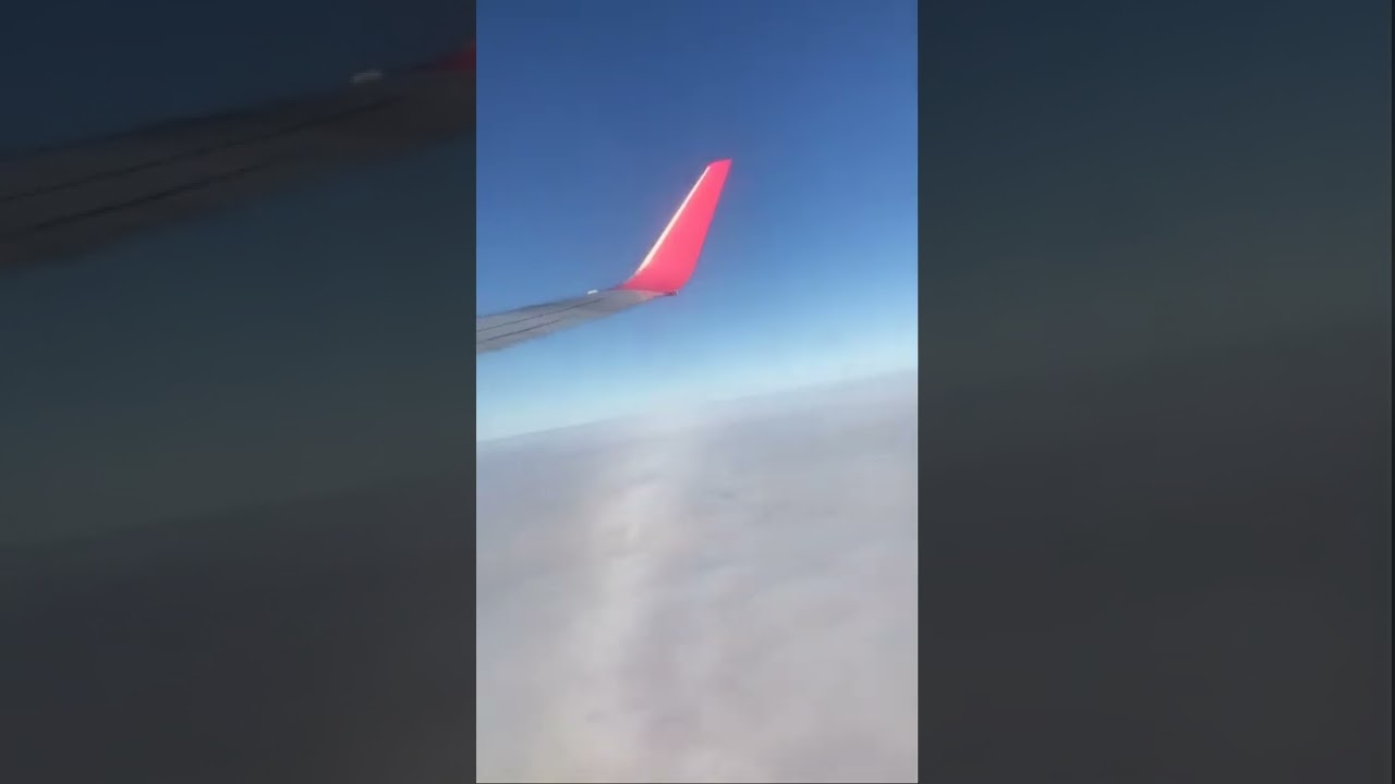 Крыло самолета в повороте. Крен самолета вправо. Вид на землю покрытую облаками из иллюминатора.