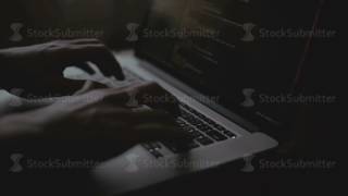 Hacker working hard on the creation of a virus using a laptop with binary codes