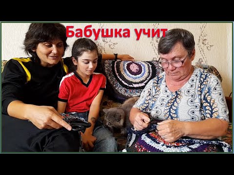 Бабушка учит вязать коврики.