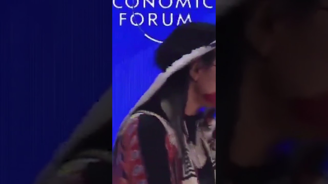 Native Woman Blows on WEF Panel Members