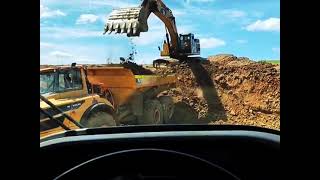 Cat 345DL slinging red dirt at a couple of Volvo 40 ton trucks