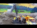 Rc excavator mines sand with rc dump truck at the mine site.