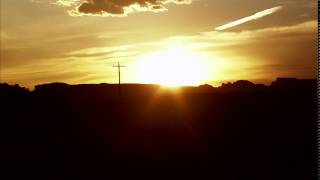 Time-lapse of the sun setting behind desert mountains.