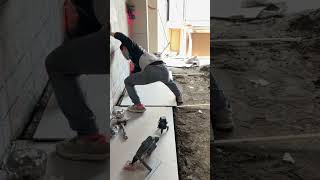 the process of installing large ceramic tiles on the ground floor of a multi-storey building #shorts