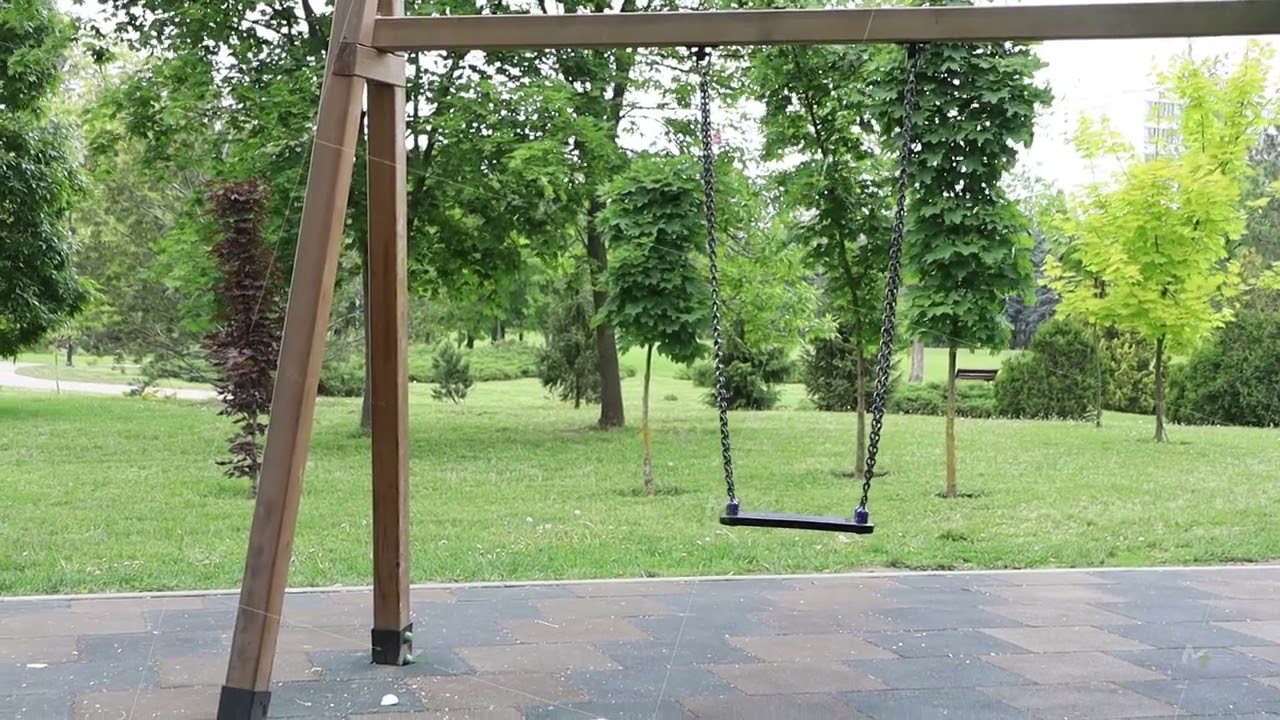An Empty Swing Set is Positioned in a Beautiful and Lush Green Park, Inviting Play