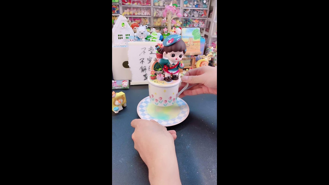 "Miniature Doll in a Teacup: Hands Preparing a Cute Figurine with Yellow Substance on a Plate"