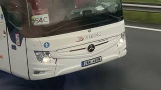 two large tourist buses meet and merge onto the highway and drive side by side on A10 by Amsterdam