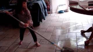 4 year old baby girl mopping kitchen floor while singing