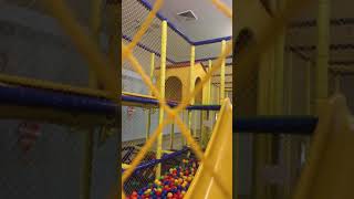Girl bumps head on tunnel in gymnasium ball pit park