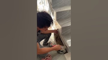 the process of installing ceramic tiles on the edge of the stairs in a large multi-storey building