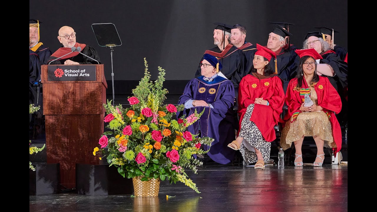 Speaker in commencement regalia standing behind a podium.