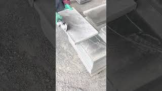 Worker cutting large stone tiles using an electric angle grinder tool