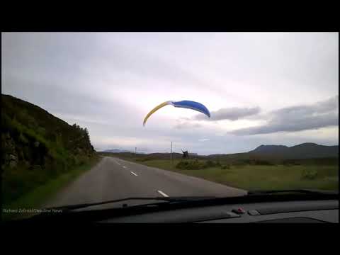 "Watch for low-flying tourists!" Moment paraglider touches down next to 60mph road in Highlands