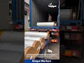Unloading Plastic Rolls: Man Pushes Rolls from Container to Truck