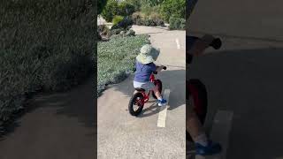 Boy wearing bucket/fishing hat rides bike around trail and crashes into street sign pole