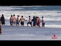 Teenage lifeguard saves boy from heavy surf | 7NEWS