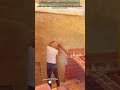 Pose d'un élément de mur voûté en briques selon un marquage préalable sur un mur enduit