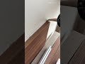 Applying silicone sealant along the edge where a wooden panel meets the white wall