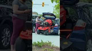 Woman attempts to put riding lawn mower in the back of small station wagon car