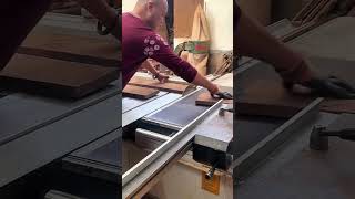 Worker guiding wooden plank through table saw precisely