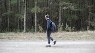 Man walking with hands in pockets - side view