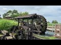 Peaceful watermill spinning amidst lush green landscape, showcasing nature's beauty.