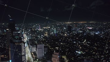 Aerial wide slow dolly shot of stunning modern city center at night with skyscrapers and busy multi
