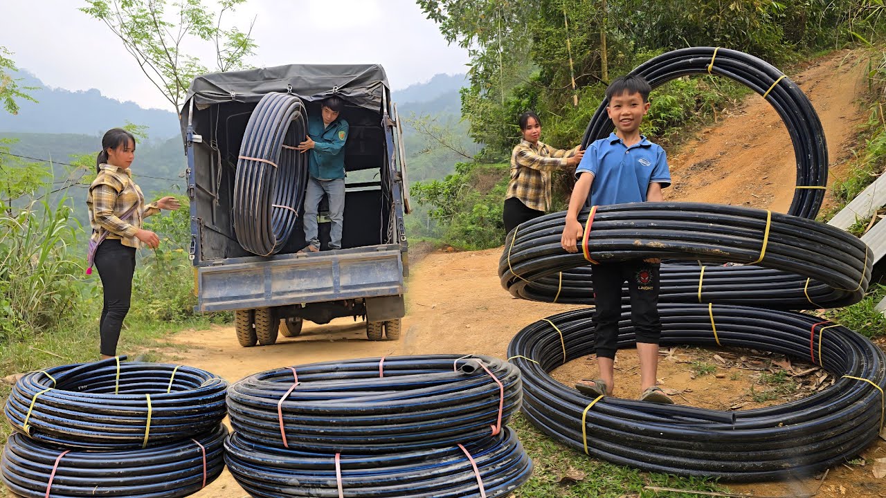 The woman uses plastic pipes to carry water from the high waterfall to her house for daily use.