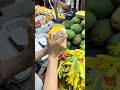 peeling ripe yellow mango fruit at market stall