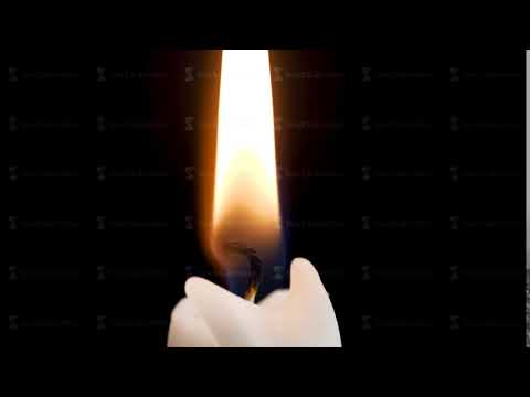 Detail of a burning candle, fire flame against black background. Close up candle with trail smoke