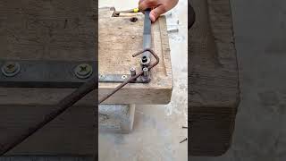 Manual rebar bending using a simple homemade jig on a wooden workbench