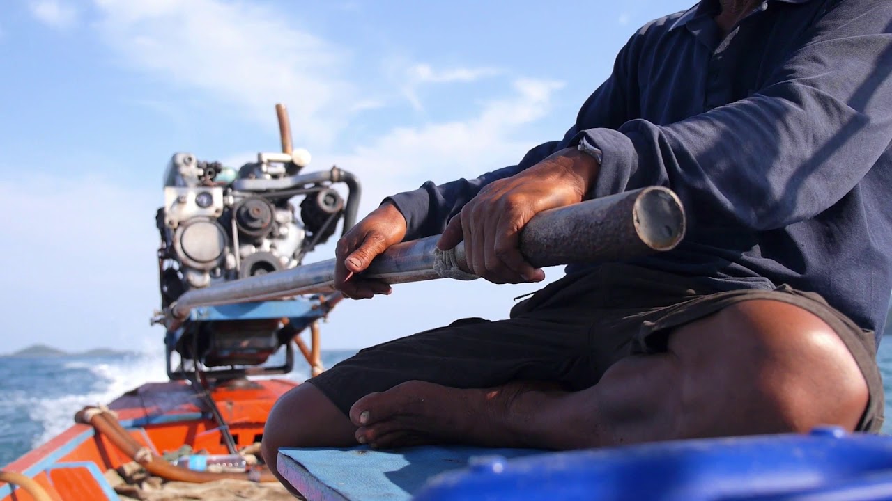 thai fisherman sailing on long tail fishing boat with motor