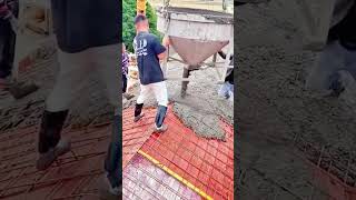 pouring wet liquid concrete mix onto metal reinforcement mesh foundation from a big crane bucket