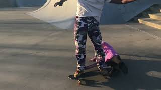 Skateboarder board slides rail near stairs at skatepark and crashes into little girl with rear
