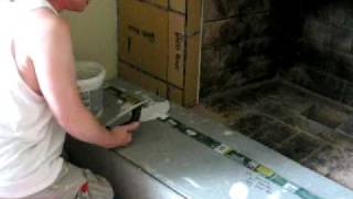 Using the adhesive/mortar to lay down the tile. How to tile over a brick fireplace.