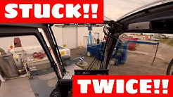 Unloading a piece of machinery from a shipping container with a crane