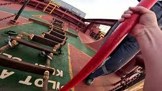 Climbing the rope ladder from a supplyboat to a bulk carrier. ship to ship bunkering in rough sea