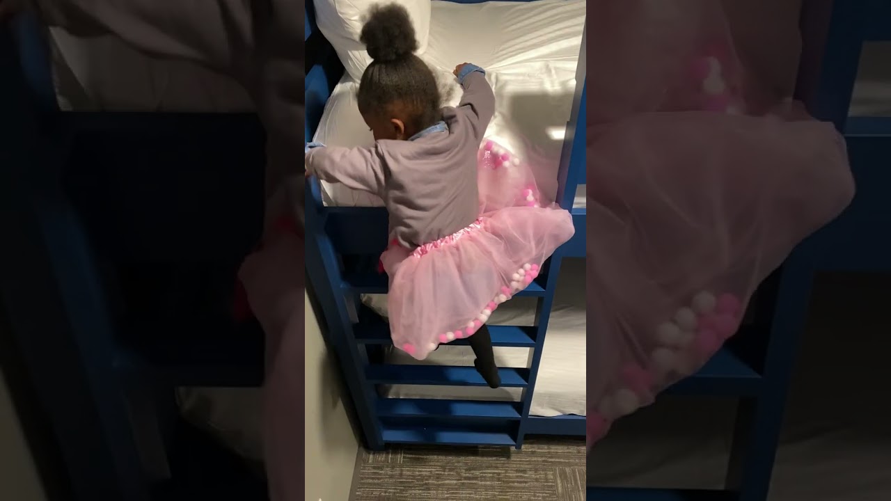 Little girl climbs down ladder of blue bunk bed and falls on the floor