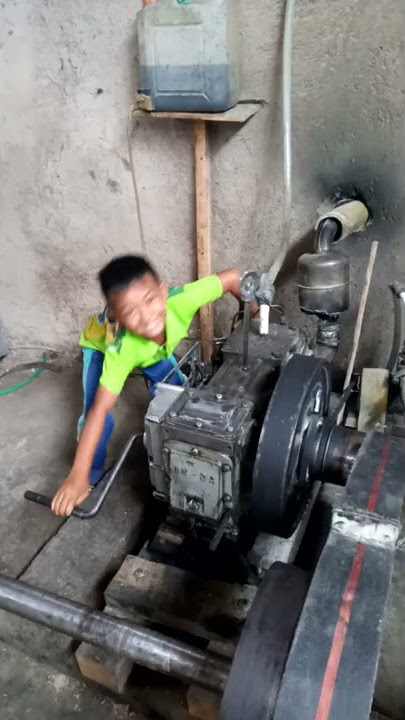 anak kecil mencoba menghidupkan mesin pabrik padi