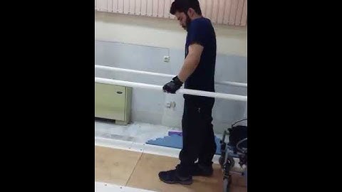 A Spinal Cord Injury Patient Is Walking Holding Parallel Bars.