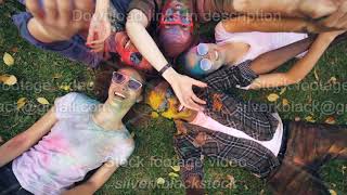 Slow Motion Zoom Out Of Delightful Men And Women With Colorful Faces And Clothing Lying On Lawn And