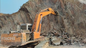 Powerful Excavator in Action: Breaking Rocks with Hydraulic Hammer and Chisel