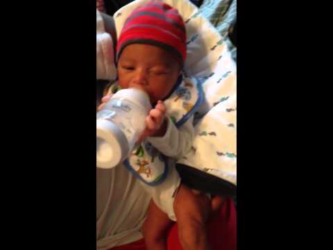 Newborn 1 week old holding own bottle